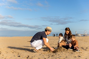 familie hurkend in het zand in Scheveningen
